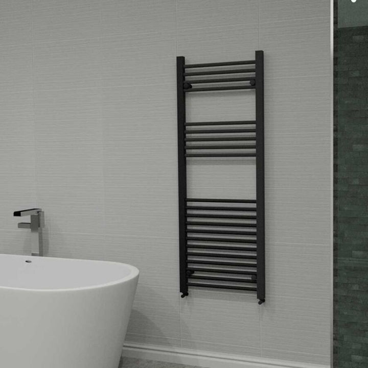 Modern bathroom with a white freestanding tub, wall-mounted towel warmer, minimalist bathtub faucet, textured grey wall tiles, and mosaic green accent tiles