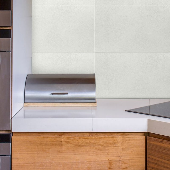 Modern kitchen interior with stainless steel paper towel holder, white countertop, wooden cabinets, and light green tiled wall