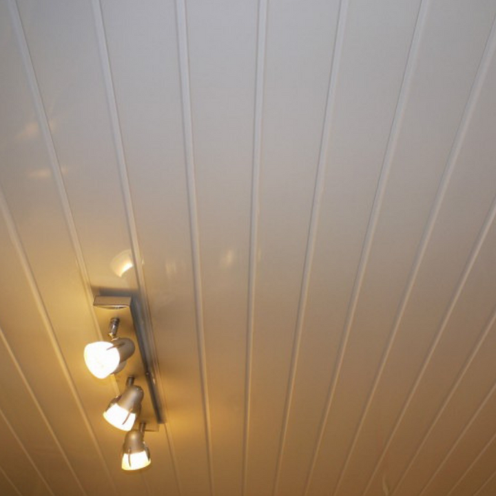 Modern interior lighting fixture on a white paneled ceiling with four adjustable spotlights turned on, creating a warm and cozy atmosphere in a contemporary home design.